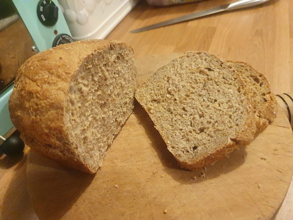 A loaf of home made bread with a couple of slices cut.