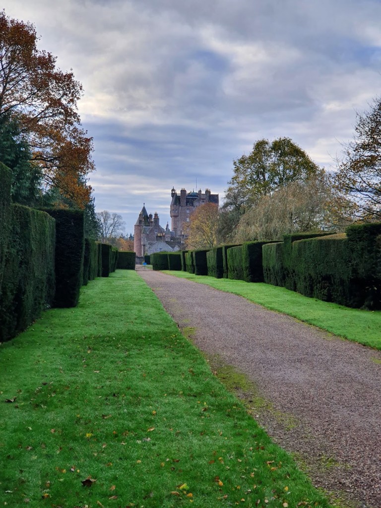 Glamis Castle from a distance with hedges in the foreground.