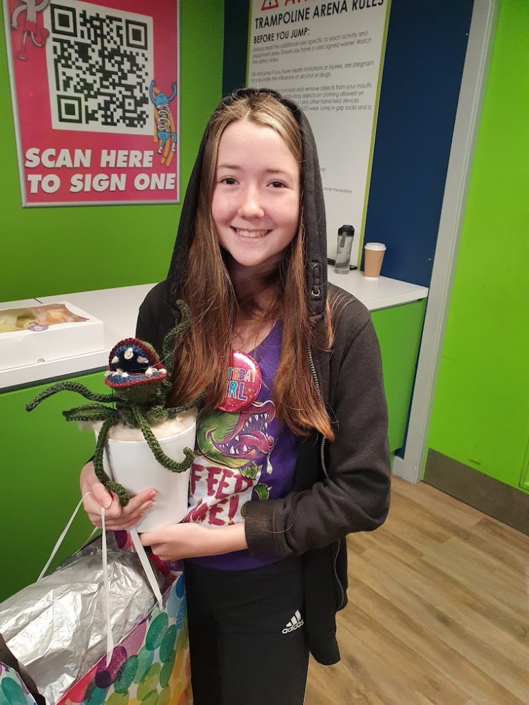 Dione holding the crochet Audrey 2  and wearing an Audrey 2 tshirt.