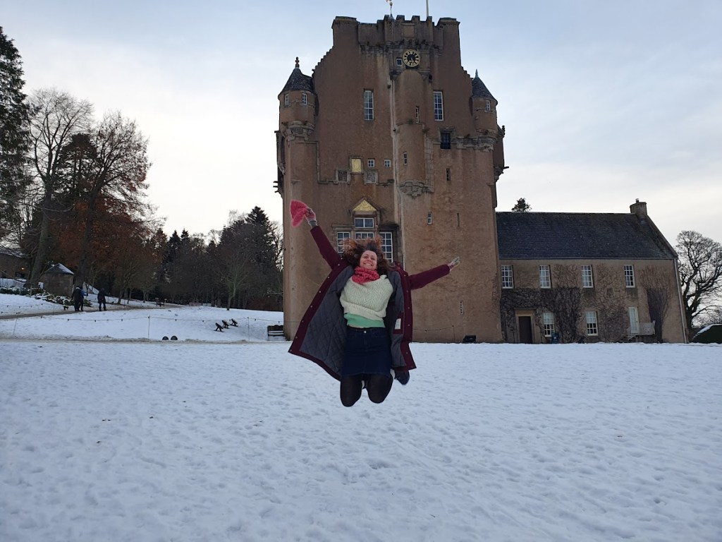 Rachel jumping with joy in front of Crathes Castle. 