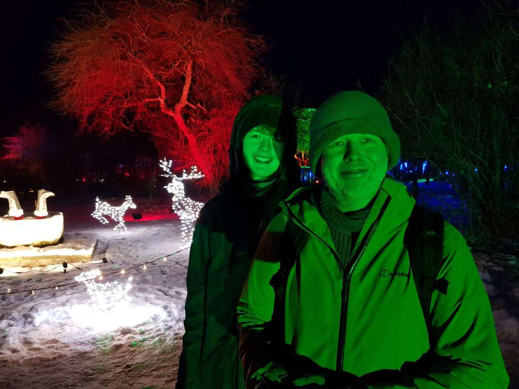 Ben and Daniel smiling and looking green because of the green lights and upside down Santa legs in the background