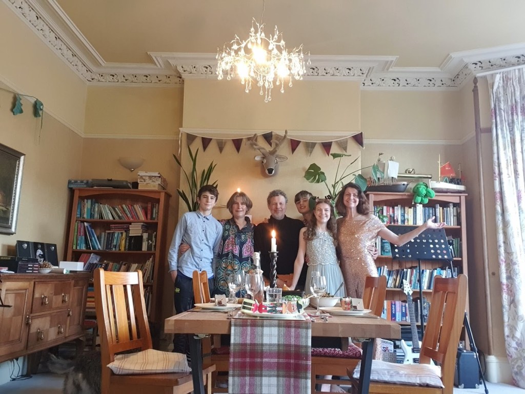 Scott, Alison, Ben, Daniel, Elizabeth, and Rachel standing behind the table smiling and about to sit down to eat. 