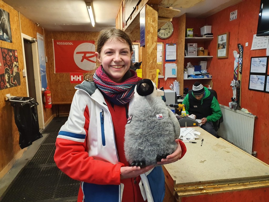 Elizabeth in the equipment rental shop holding Slipper the penguin