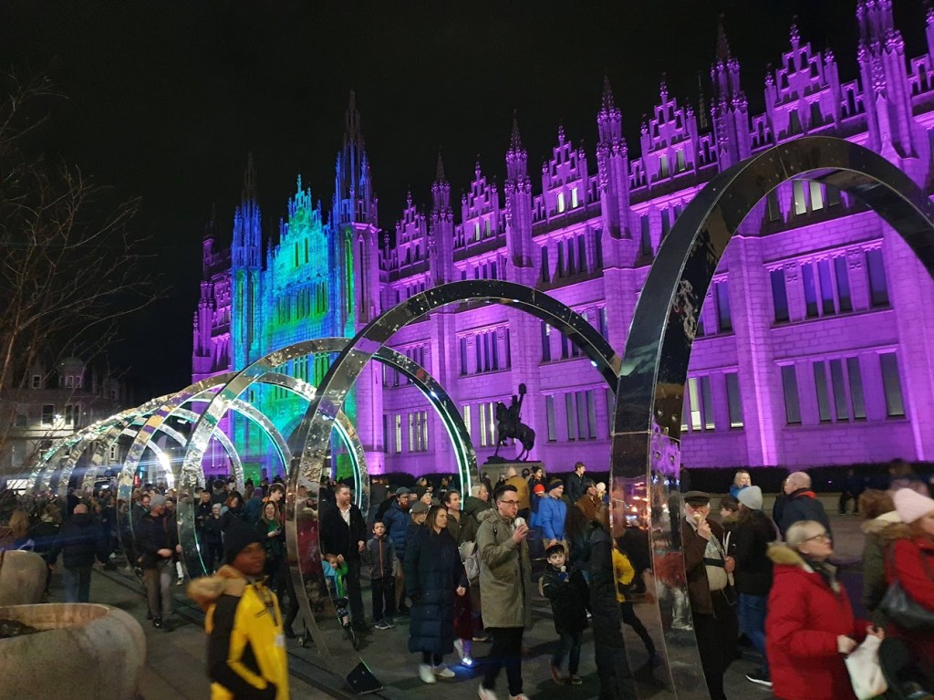 The front of Marischal College all lit up with silver arches in the foreground