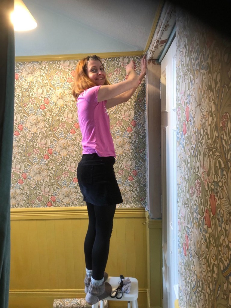 Me standing on a stool wallpapering the entranceway
