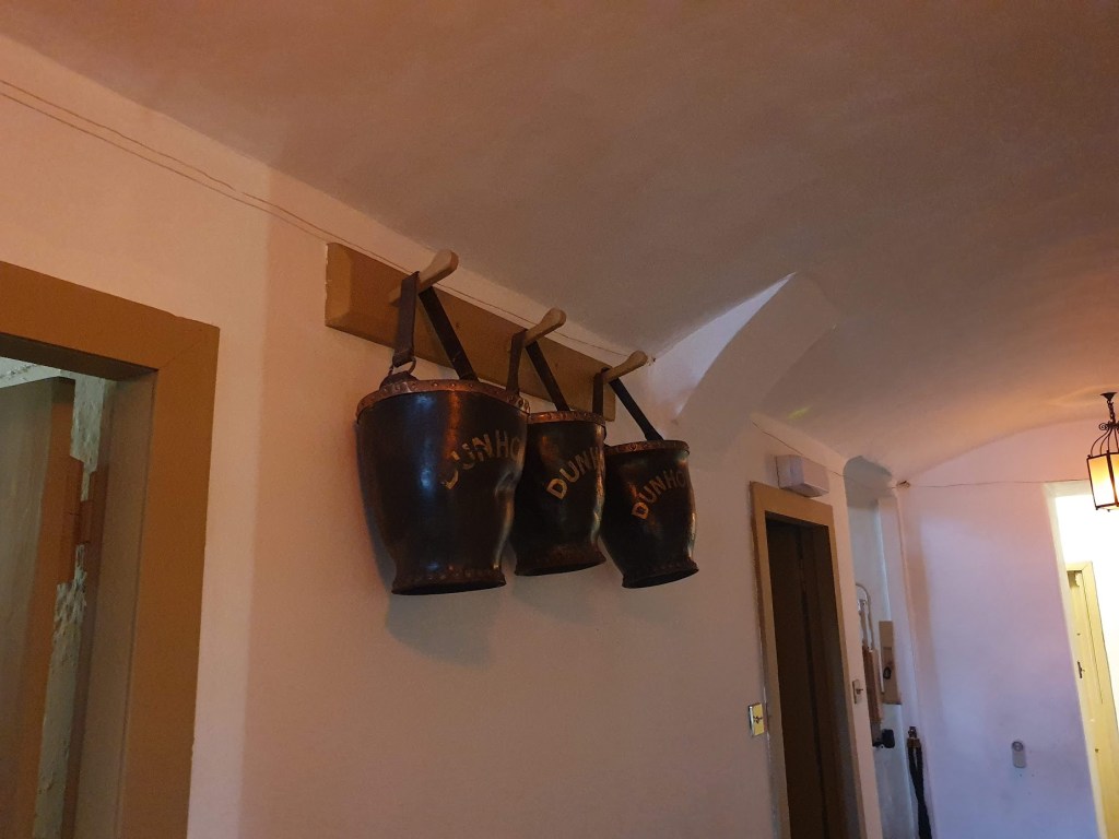 Three black buckets hanging from hooks in the servant's quarters