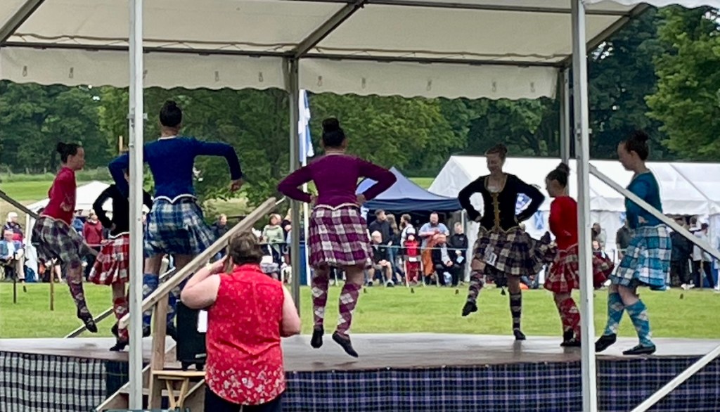 Elizabeth dancing on stage. She's in a black jacket with her hands on her hips.