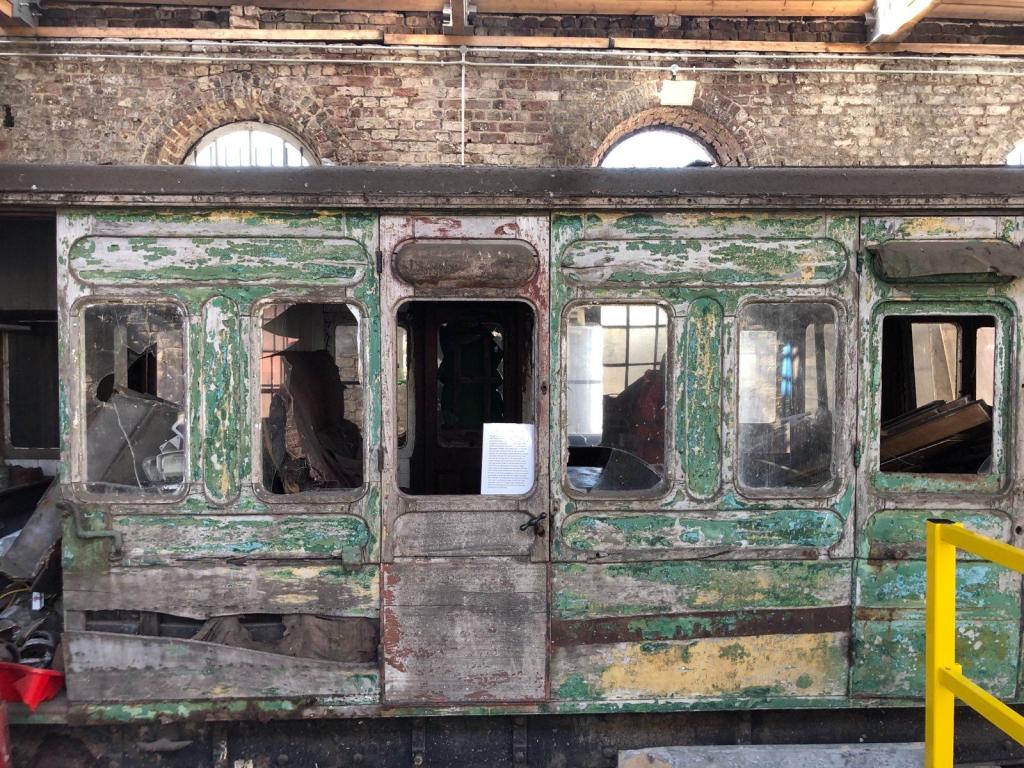 A dilapidated train carriage with peeling green paint
