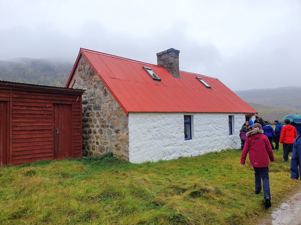 Felagie Bothie with a red roof and white stone wall. 