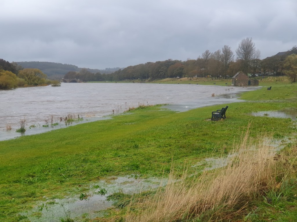 The River Dee partly flooding the neighbouring parkland and boat house.