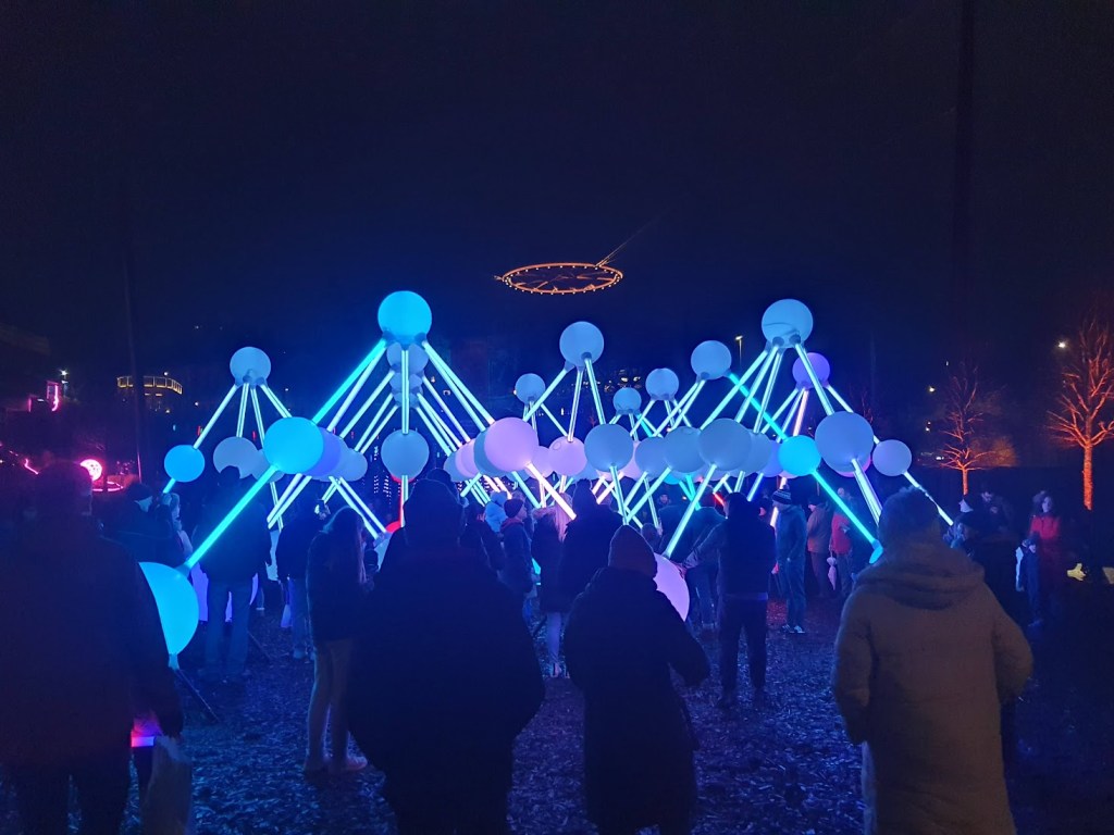 Lots of balls on poles in the shape of pyramids and all lit up in white and pink lights.
