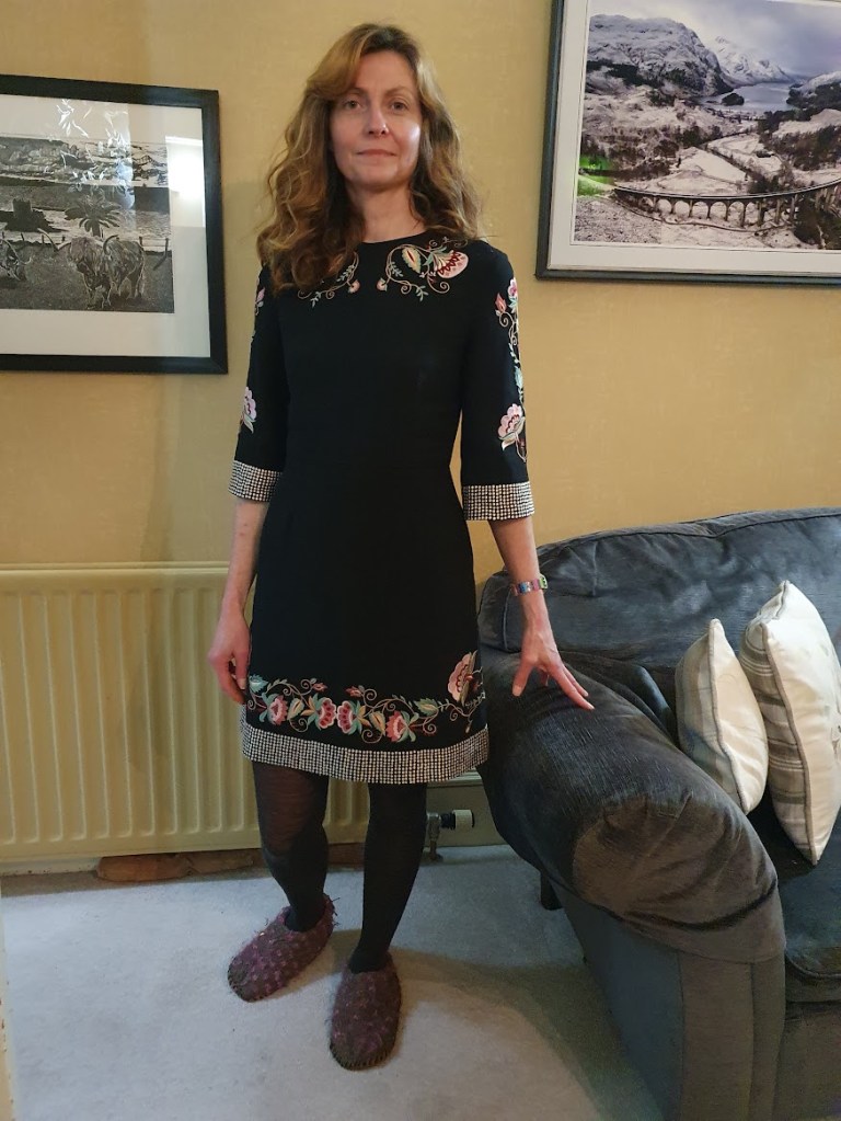 A simple black dress with pretty embroidery around the edges consisting of flowers and silver dots.