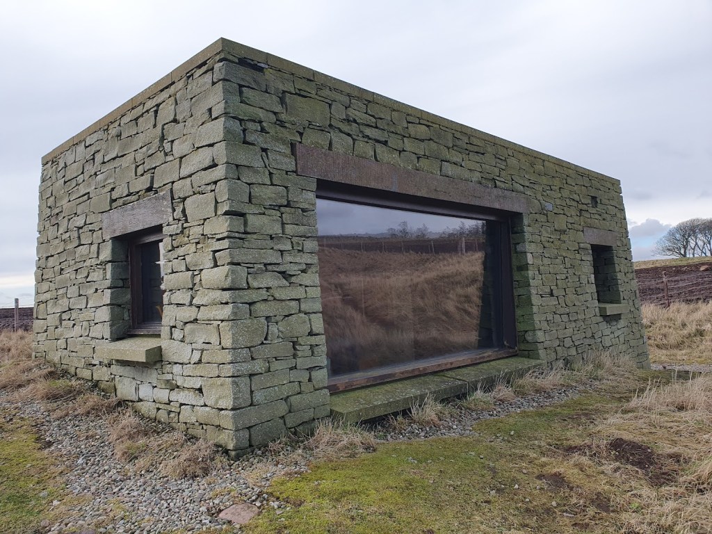 A stone building with a large glass window for viewing.