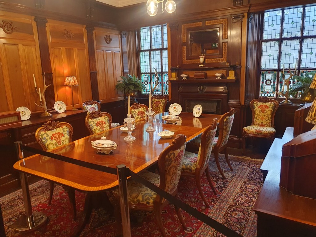 Queen Victoria's waiting room with a dining table, wood panelling, and stained glass windows.