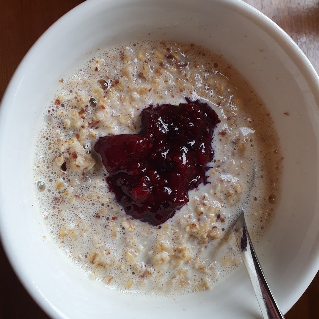 A bowl of porridge with berry compote in the middle.
