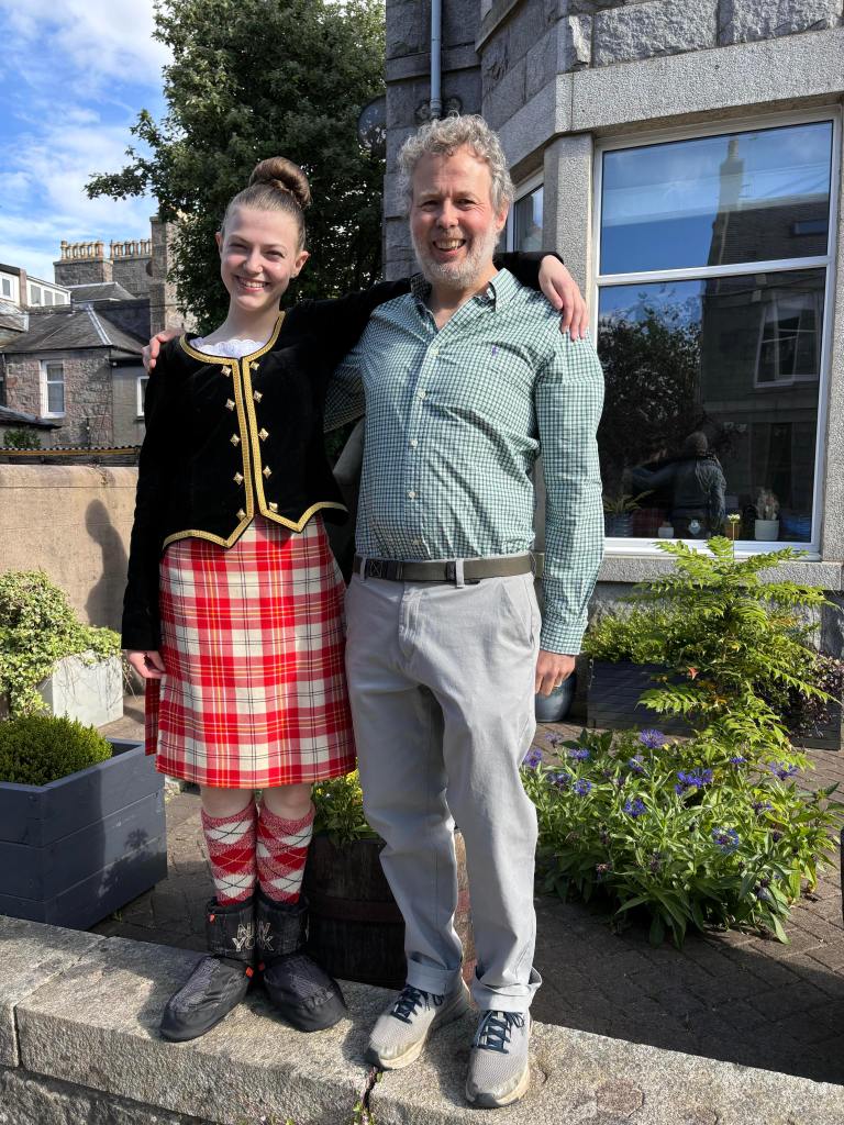 Elizabeth and Ben posing outside our house with Elizabeth in her full kilt outfit.