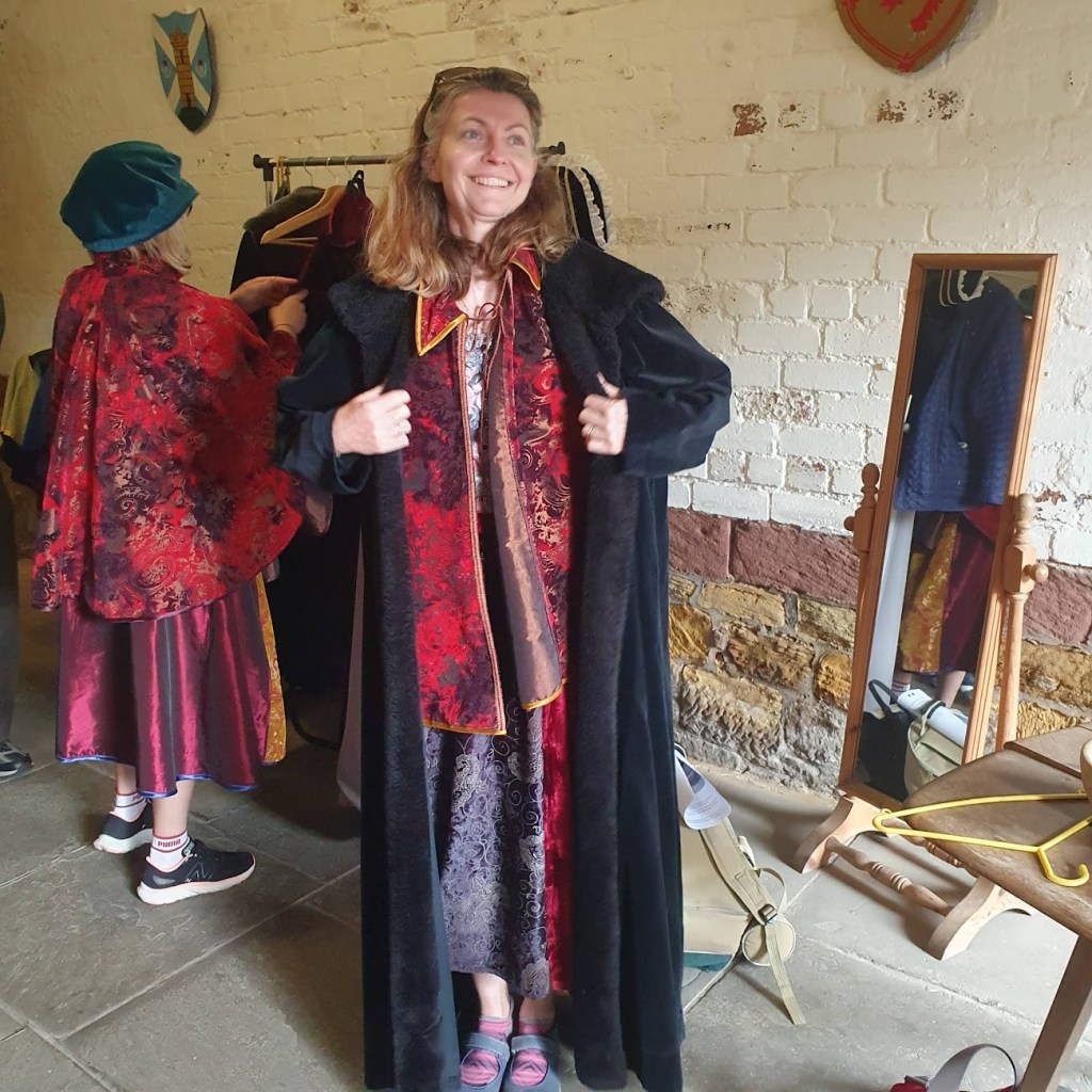 Rachel in a black coat and various other dress-up items. 