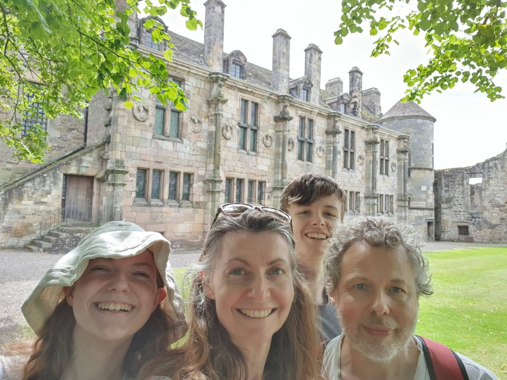 A selfie of Elizabeth, Rachel, Daniel, and Ben with Falkland Palace in the background.