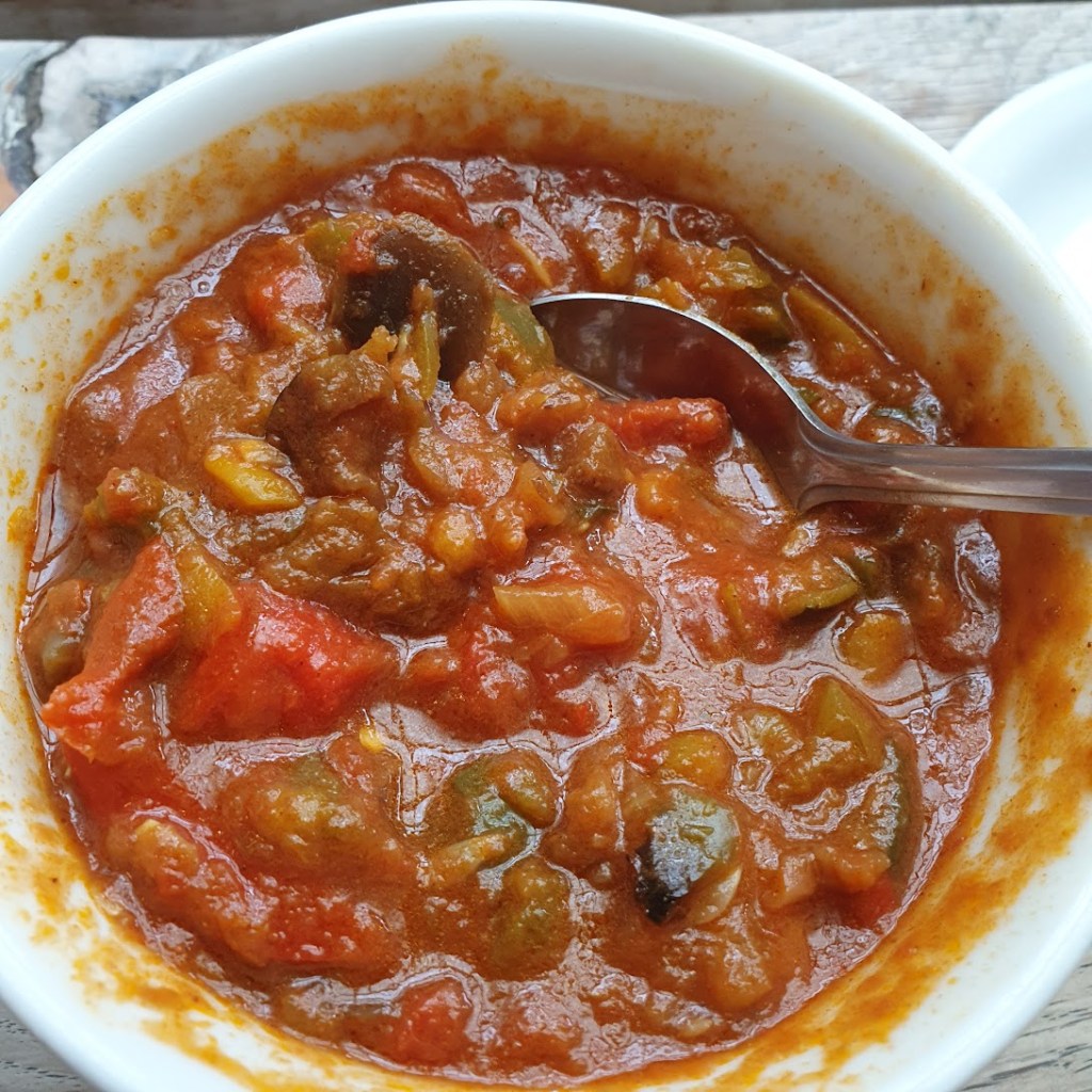 A bowl of curry with lots of vegetables.