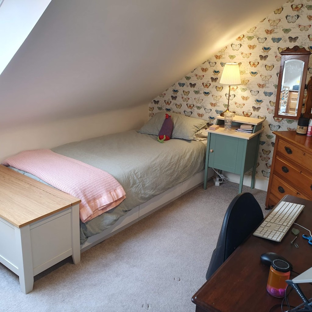 Butterfly wallpaper with a bed, bedside table and dressing table.