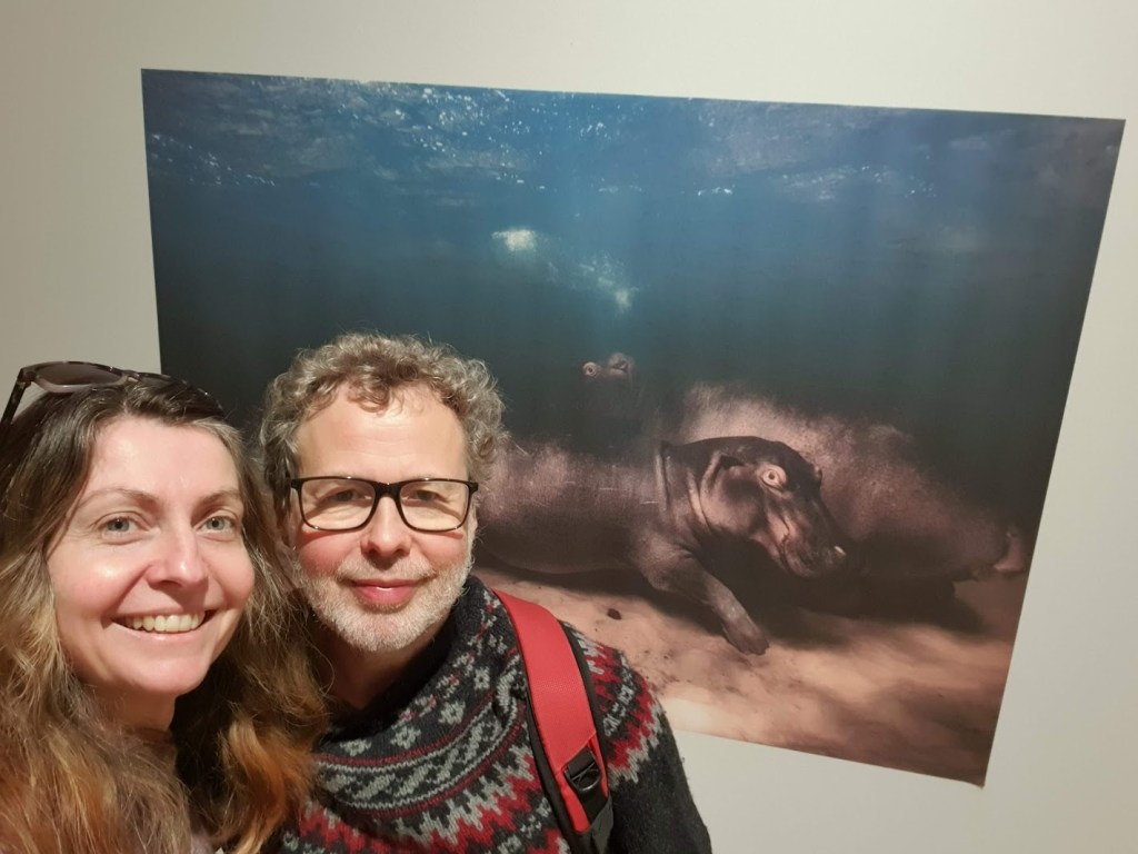 A selfie of Ben and Rachel with the hippo photo behind.