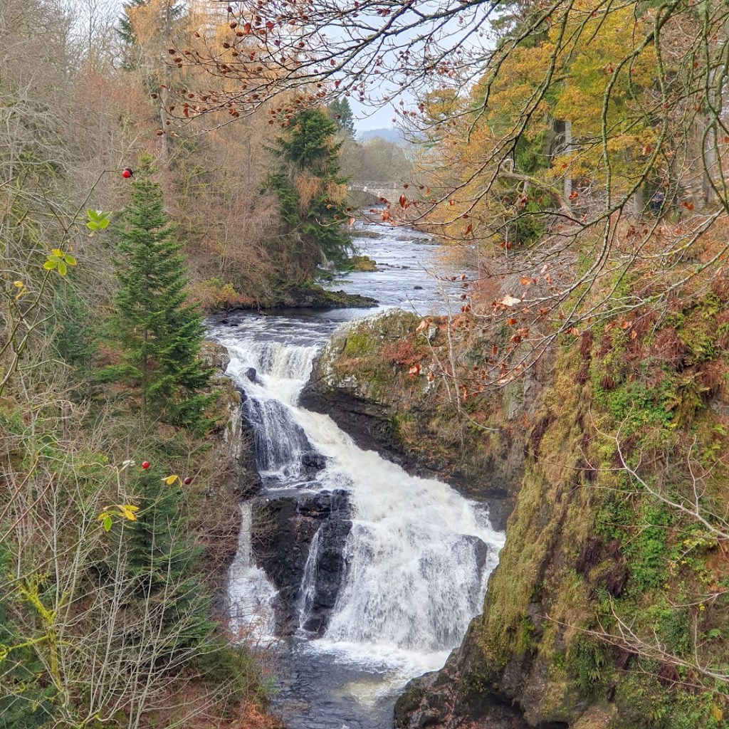 A long shot of the waterfall with a bridge in the far distance.