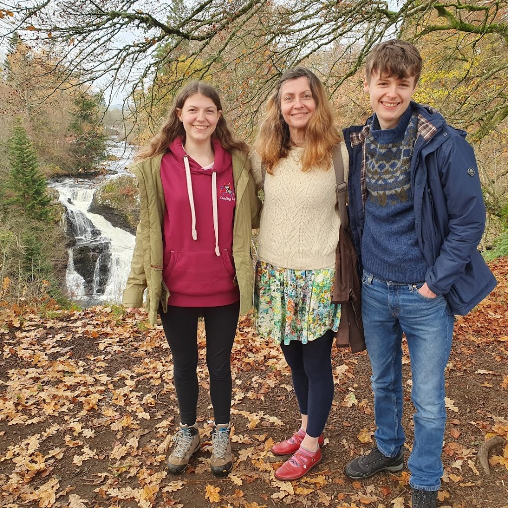 Elizabeth, Rachel and Daniel in the foreground, smiling, with the waterfall behind.