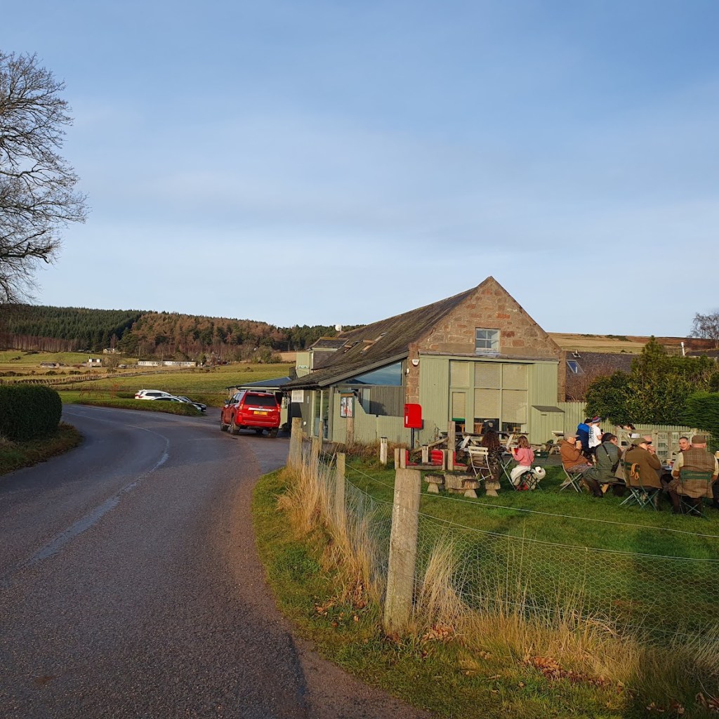 Granite building with people sitting at ourdoor tables. 