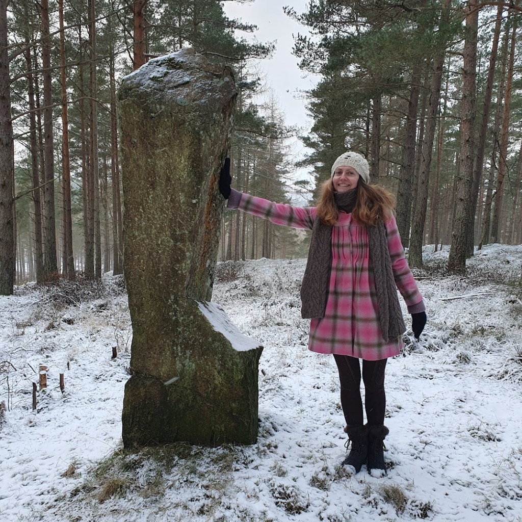 Rachel pushing against a standing stone.