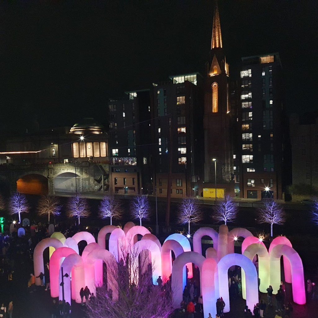 Union Terrace Gardens with lots of upside down "U" letters that are lit up in pinks, purples and greens.