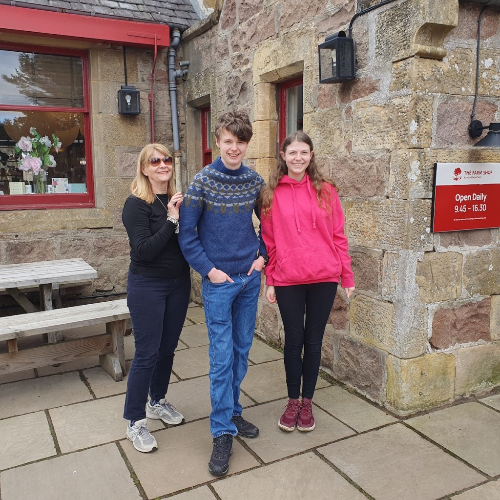 Mum, Daniel and Elizabeth smiling next to the farm shop.
