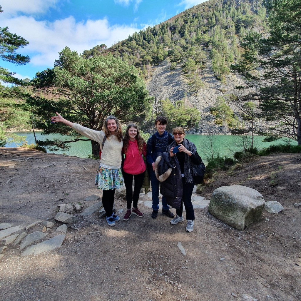 A wide angle shot of Rachel, Elizabeth, Daniel and Mum smiling in front the loch.