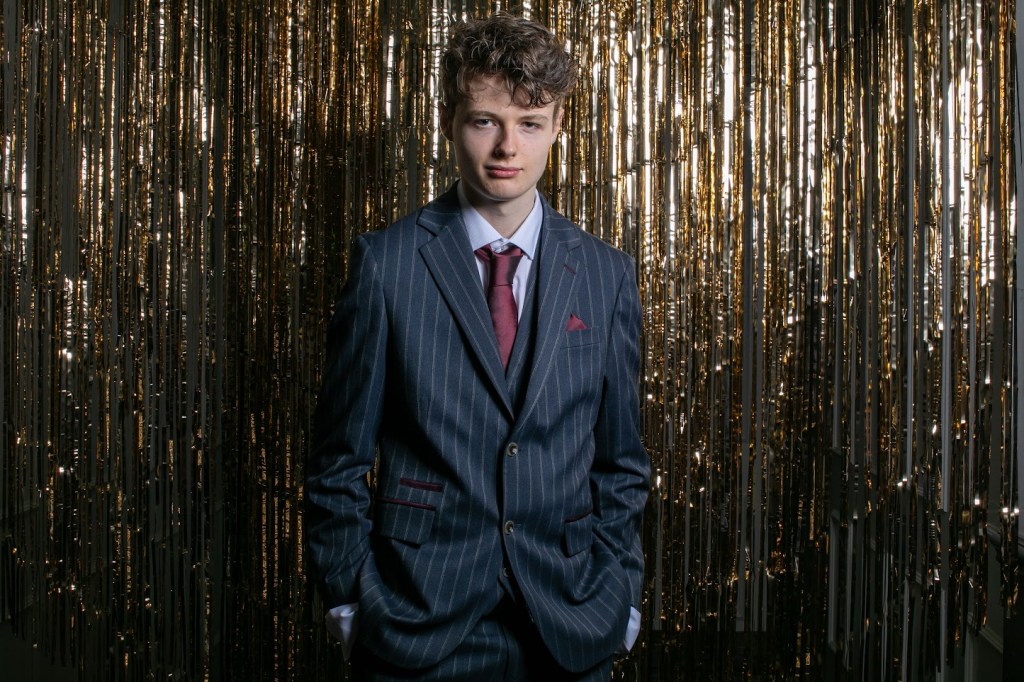 Daniel standing in front of the gold curtain.