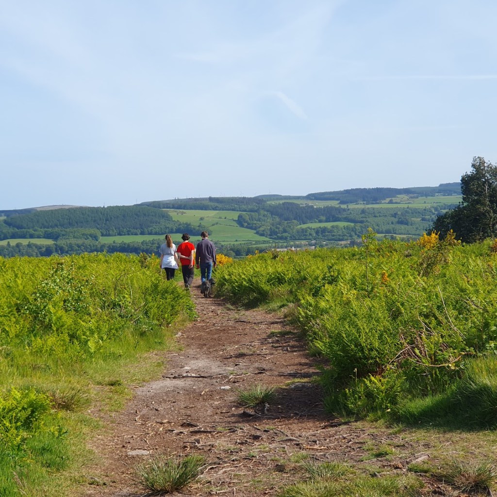 Elizabeth, Scott and Daniel walking ahead with hills in the distance.