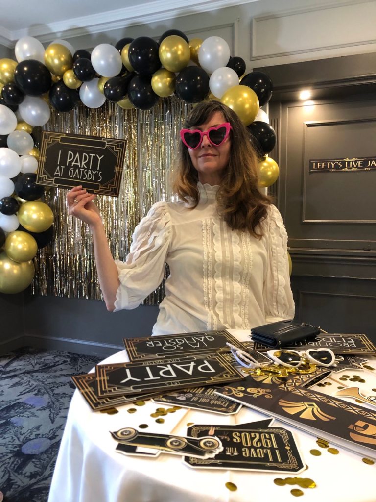 Me wearing pink heart glasses and holding a "I party at Gatsby's sign".