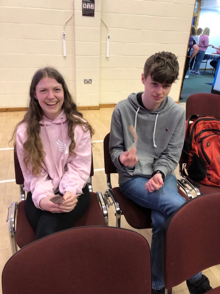 Elizabeth and daniel seated in the back row. Elizabeth is smiling and Daniel is looking bored.