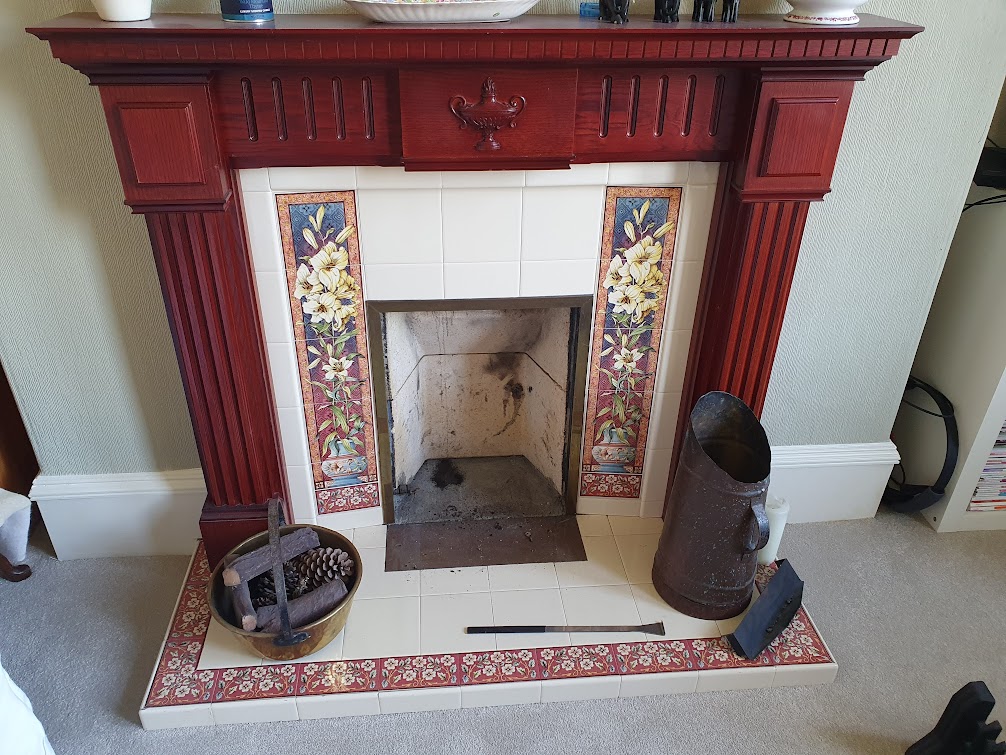 The old fireplace with red timber surround and floral tiles.