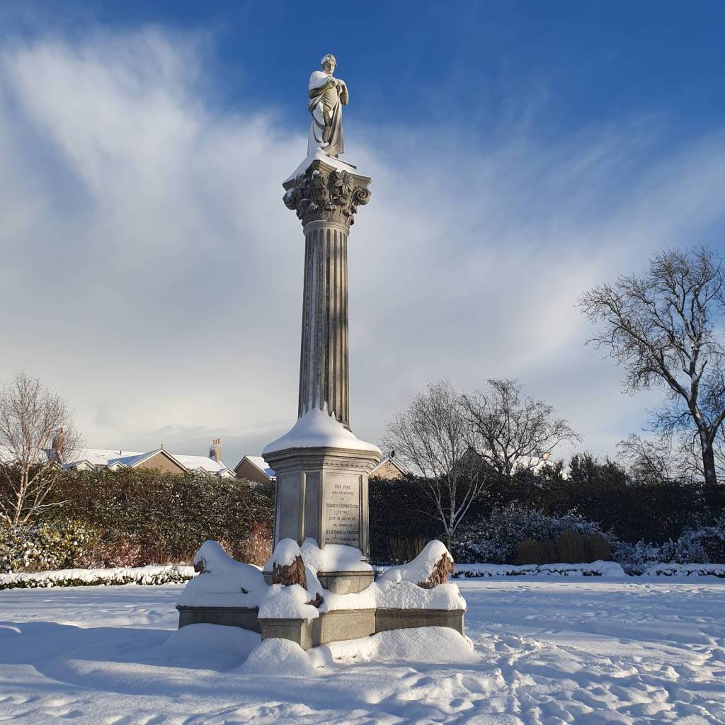 Elizabeth Duthie statue at Duthie park covered in snow with a sunny blue sky behind