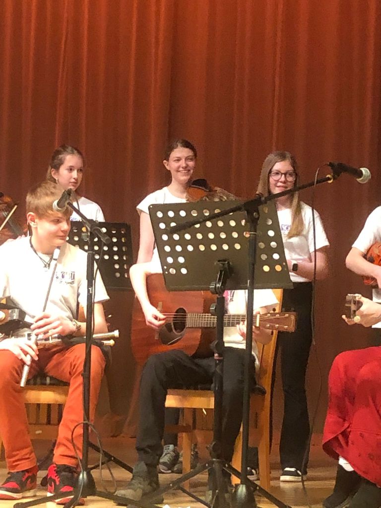 Elizabeth smiling with her violin on stage at Newton Dee.