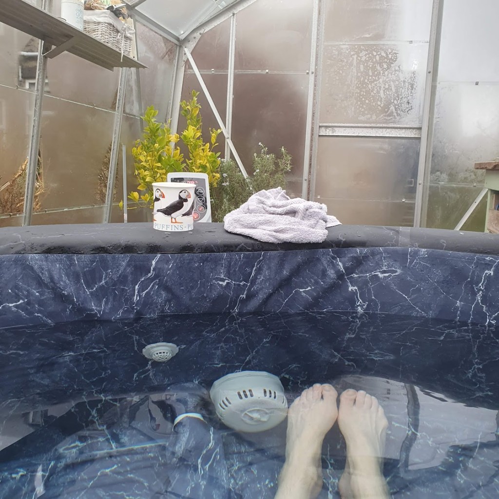 View from the hot tub with my feet visible under the water and a cup of coffee sitting on the side