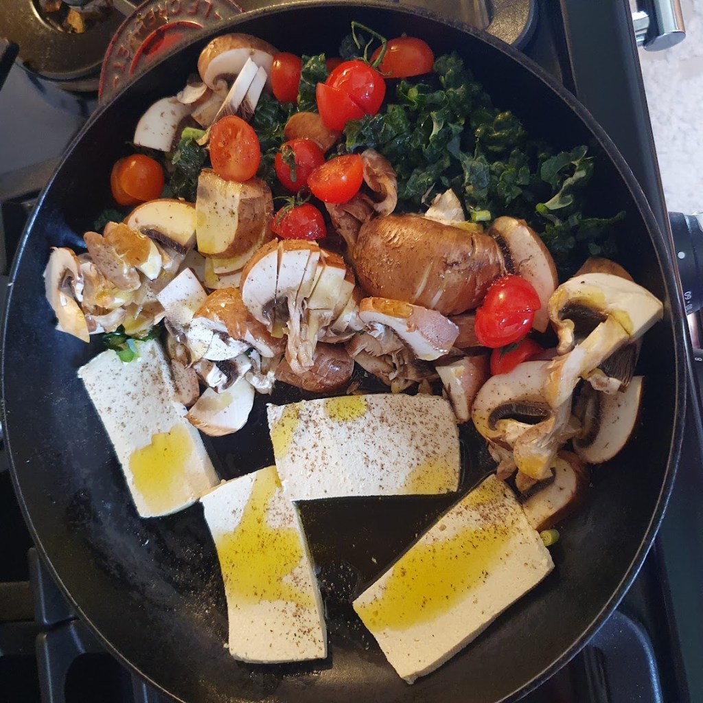 The uncooked tofu and vegetables in the frying pan