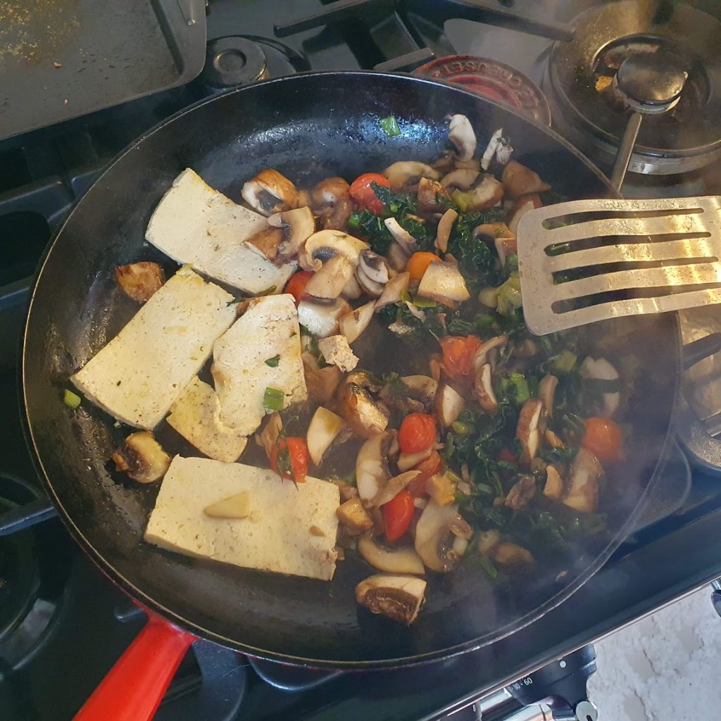 The frying pan with four slices of tofu and all the vegetables