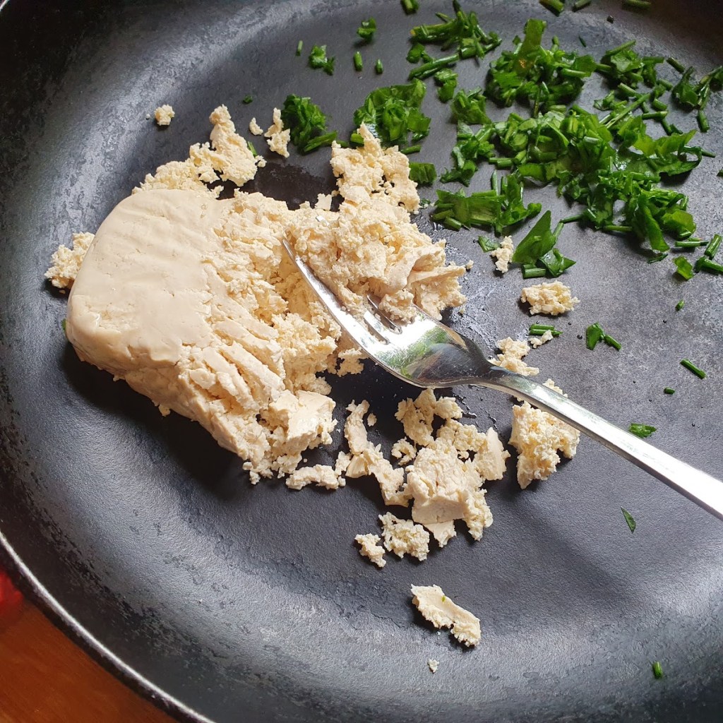 Tofu on a pan getting mashed up
