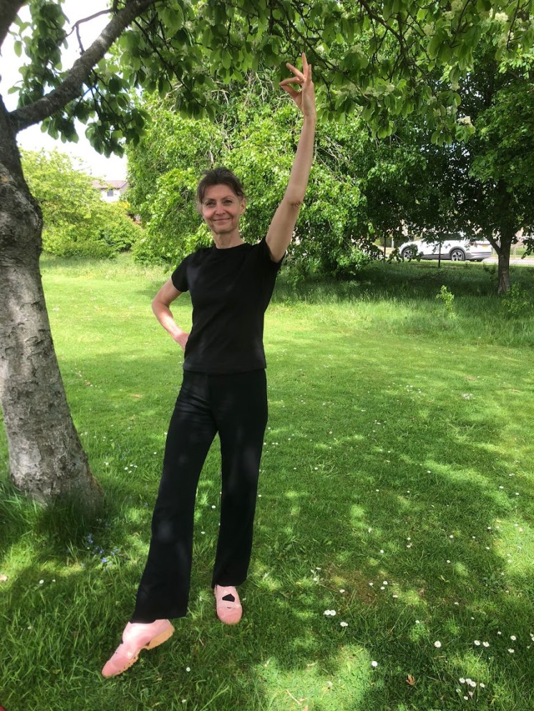 Me doing a highland dance pose on a field beside the hall.