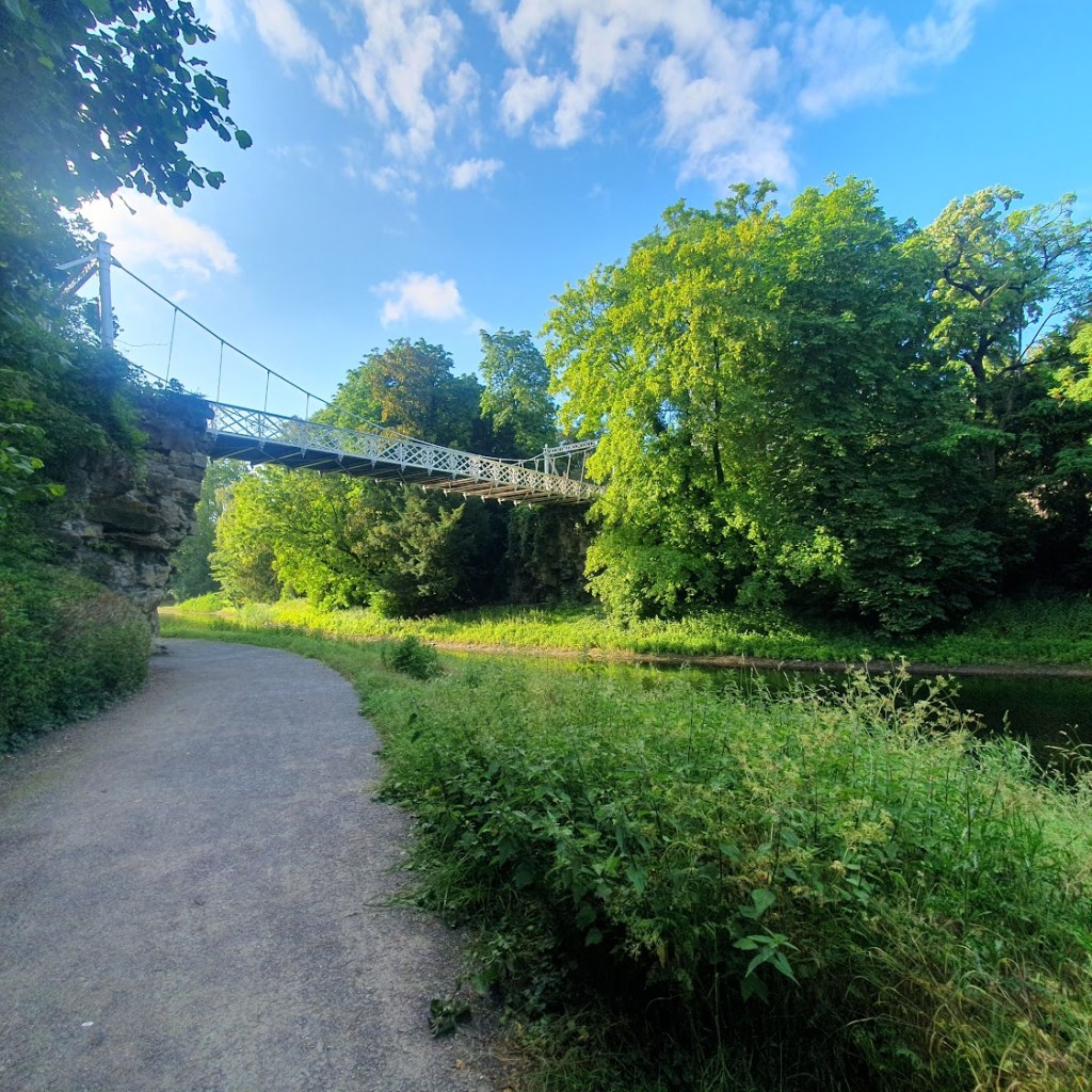 A white iron suspension bridge over the lake