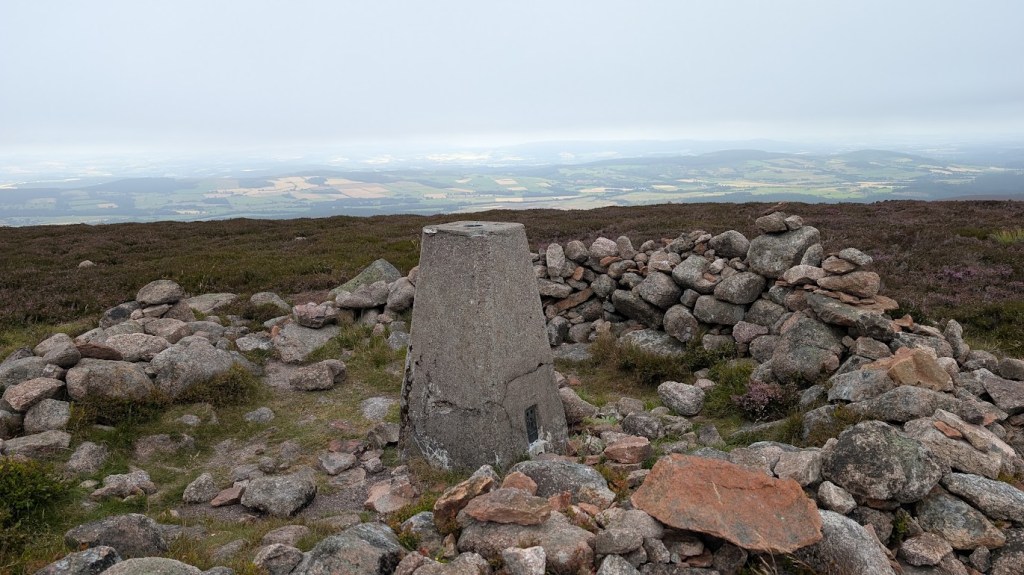 A viewpoint with fields in the distance and a rocky cairn in the foreground