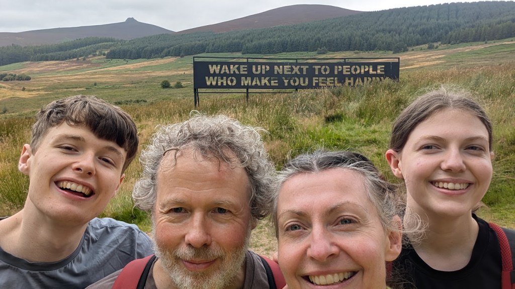 A selfie of the four of us in front of the sign and Clachnaben off to the left