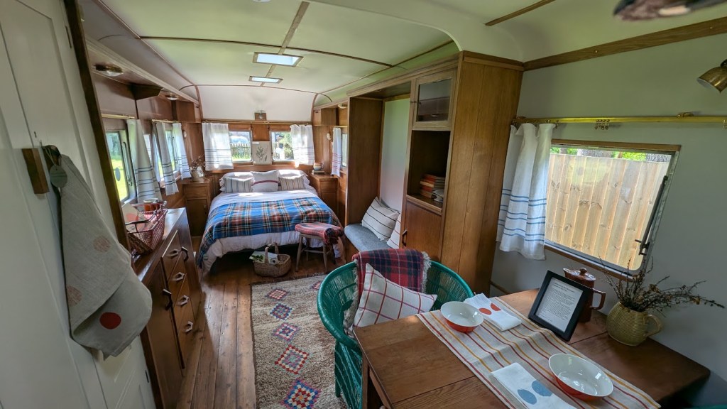 Inside the gorgeous vintage caravan with all the timber fittings and a table laid out, the bed beautifully made.