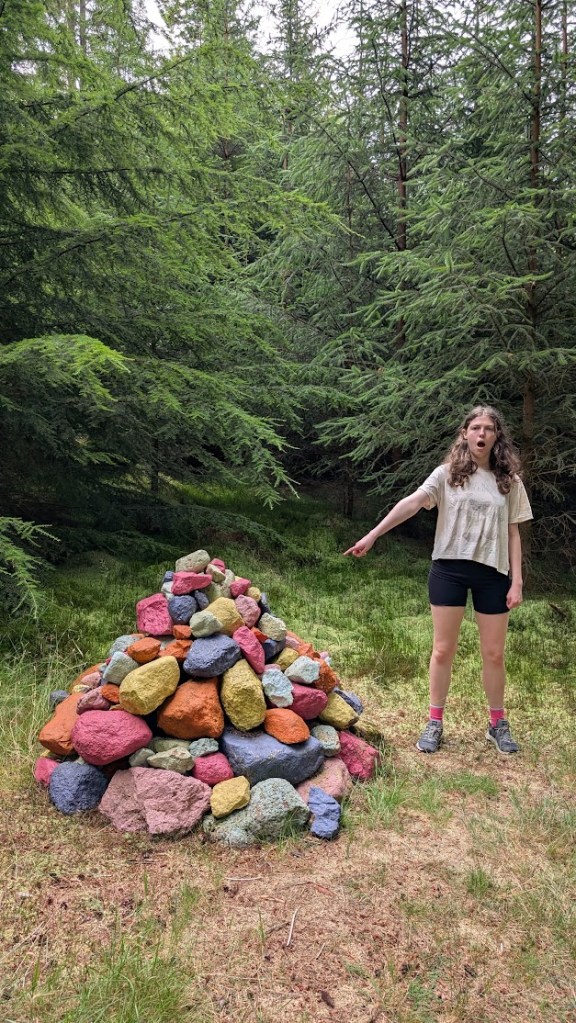 A pile of coloured rocks with Elizabeth pointing at it.