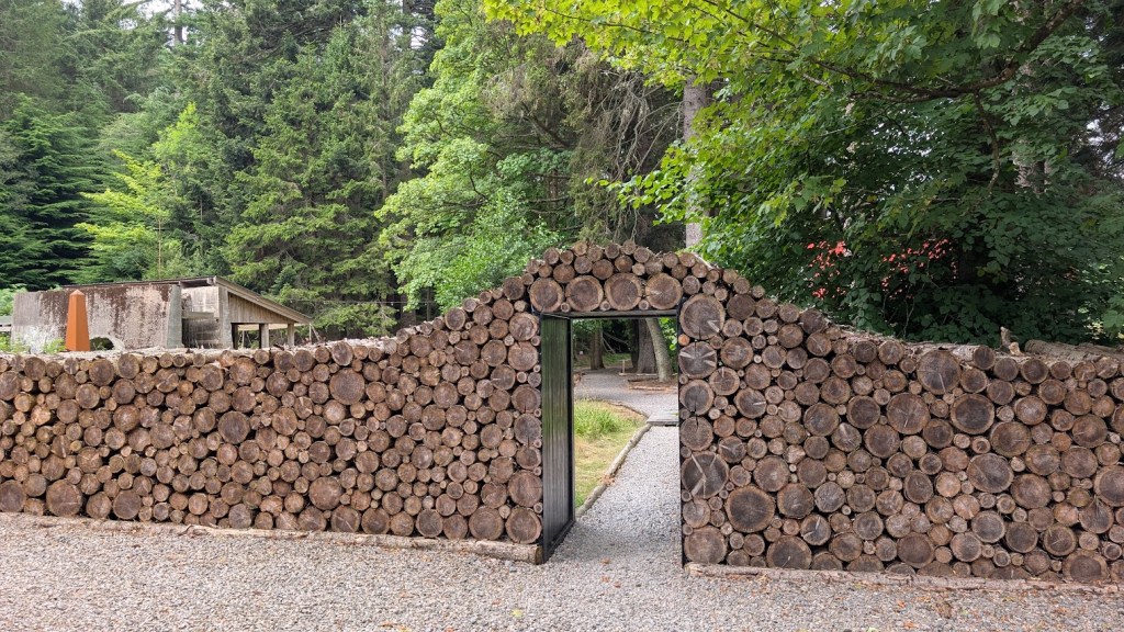The entrance to the sawmill which is made of logs stacked neatly around an entranceway